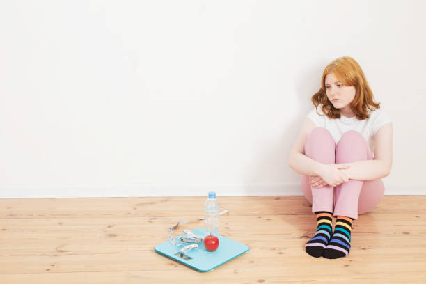 sad teenager girl with scale on wooden floor