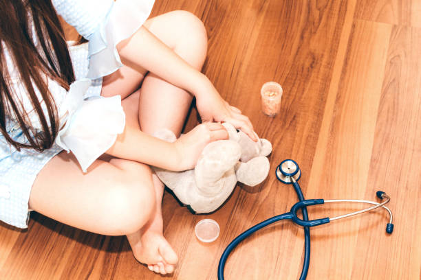Little girl playing doctor with teddy bear doll